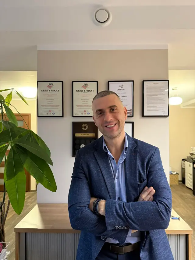 Tomasz Bieńkowski na tle certyfikatów jakości w biurze IQ Consulting
